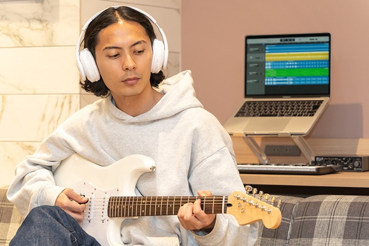 自宅で動画を見ながら、ギターの練習と運指トレーニングをする男性