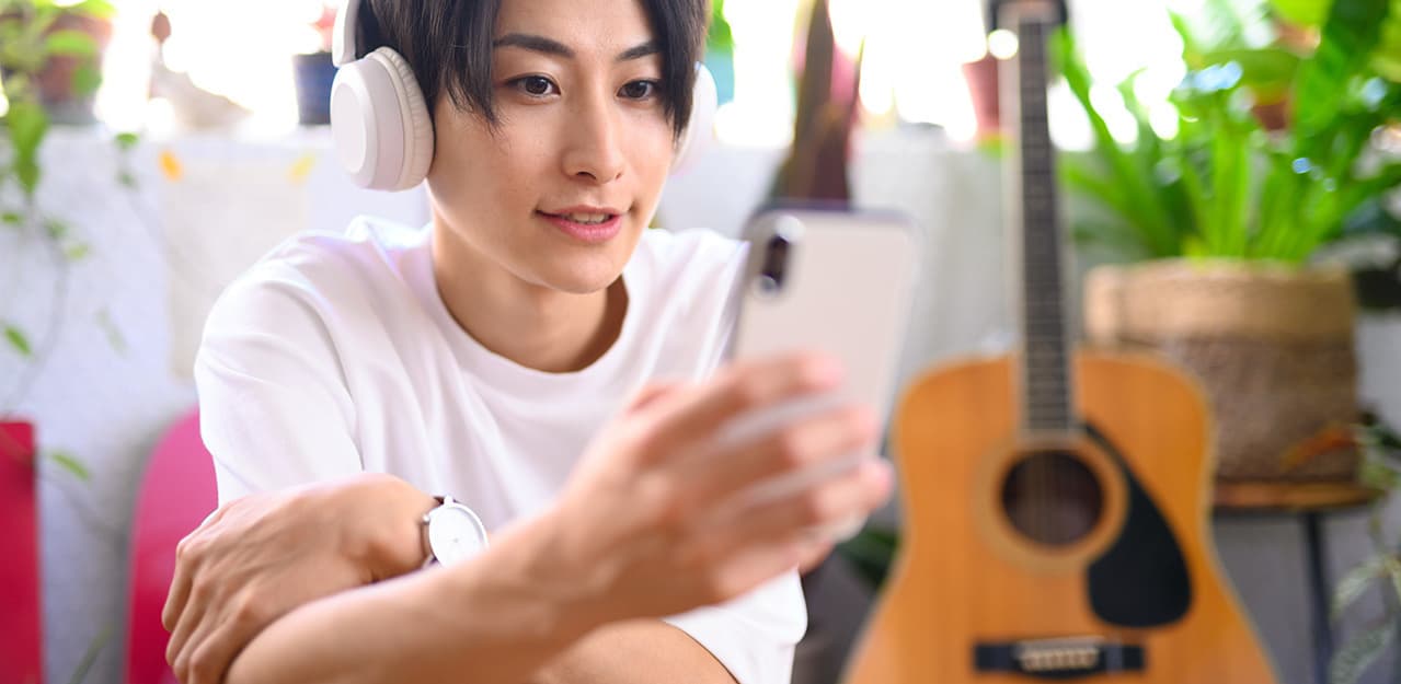 スマホでオンラインギターレッスンを受講する生徒|動画見放題プラン